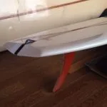 Long raked orange flex single fin under a white board indoors